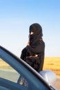 An islamic woman approaches a car and on a track