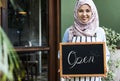 Islamic woman small business owner holding blackboard with smiling