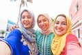 Islamic young friends taking selfie with smartphone camera outdoor - Happy arabian girls having fun with new trend technology -