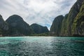 an island with cliffs towering out over the water and sandy beach