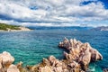 Island cliffs and waves in the ocean, seen from coastline. Calm water, clear sky and waves on a sunny summer day Royalty Free Stock Photo