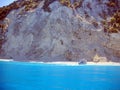 Island and turquoise sea with small cruiser and tourists on beach