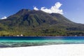 Island with white sand and volcano in the background