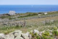 Isles of Scilly, UK - Old stone wall deviding meadows near Peninnis Head, ocean with sailboat in the background Royalty Free Stock Photo