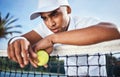 This isnt going my way. a handsome young man leaning on a tennis net and looking disappointed after practice.