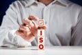 ISO standards, quality control certification approval. Businessman puts a cube on top of wooden cubes with the word iso Royalty Free Stock Photo