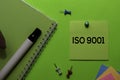 ISO 9001 write on sticky notes. Isolated on green table background