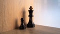 Isolate chess black pawn and king in wooden background Royalty Free Stock Photo