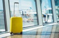 isolate traveler tourist yellow suitcase at floor airport on background large window, bright luggage waiting in departure lounge Royalty Free Stock Photo