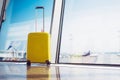 Isolate traveler tourist yellow suitcase at floor airport on background large window, bright luggage waiting in departure lounge Royalty Free Stock Photo