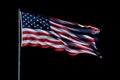 Isolated American flag with stars and stripes waving in wind on pole against black background. AI Generated Royalty Free Stock Photo