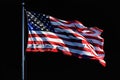 Isolated American flag with stars and stripes waving in wind on pole against black background. AI Generated Royalty Free Stock Photo