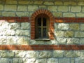An isolated arched church monastery chapel window and massive stone wall background.