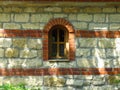 An isolated arched church monastery chapel window and massive stone wall background.