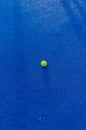 An isolated ball on a blue paddle tennis court