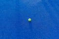 An isolated ball on a blue paddle tennis court