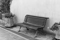 Isolated black bench in the courtyard near two vases with plants and flowers in front of the wall Italy, Europe Royalty Free Stock Photo