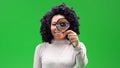 Isolated black female on a green screen smiling and holding a magnifier in front of her left eye Royalty Free Stock Photo