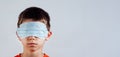 Isolated blindfolded child with surgical mask over the eyes and bare mouth and nose