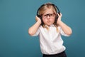 Pretty, cute little girl in white shirt, glasses, black trousers and headphones Royalty Free Stock Photo