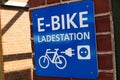 Isolated blue and white sign on brick wall with information for e-bike charging station german word: Ladestation - Germany Royalty Free Stock Photo