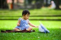 Isolated candid portrait of sweet and adorable Asian Chinese baby girl 3 or 4 months old playing with hat alone at city park