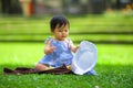 Isolated candid portrait of sweet and adorable Asian Japanese baby girl 3 or 4 months old playing with hat alone at city park