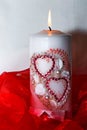 Isolated candle with hearts. Red ribbon. A burning candle. A bright flame. Decorative candle