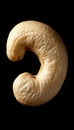 Isolated cashew nut showcasing unique shape, creamy color, and subtle textures on black background. Royalty Free Stock Photo