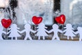 Isolated Chain of Origami Paper Boys and Girls Holding Hands With a Red Heart Between Them and the Hoarfrost on Window in