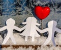 Isolated Chain of Origami Paper Boys and Girls Holding Hands With a Red Heart Between Them and the Hoarfrost on Window in