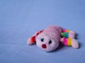 Isolated children`s toy against a blue texture background, teddy bear from childhood, an old torn pink centipede