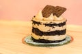 Isolated chocolate cake with cream and cookies on a wooden table. Pink background. Concept of bakery. Tasty and delicious cake.