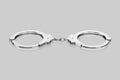 Isolated chrome Handcuffs on a Light Reflective Surface