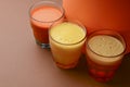Isolated citrus juice. Three glasses with orange, grapefruit and lemon juice isolated on orange background