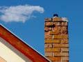 Isolated clay brick chimney with weathered and spalling surface. wood trim on house gable end wall. blue sky Royalty Free Stock Photo