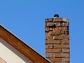 Isolated clay brick chimney with weathered and spalling surface. wood trim on house gable end wall. blue sky Royalty Free Stock Photo