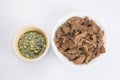 Isolated close up flat lay top view shot of a bowl of sliced beef fillet pieces and a cup of Vietnamese Nuoc Cham dipping sauce on