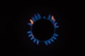 Isolated close up shot of a blue and orange circular fire with small flames on the perimeter coming from a kitchen gas stove and Royalty Free Stock Photo