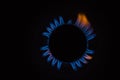 Isolated close up shot of a blue and orange circular fire with small flames on the perimeter coming from a kitchen gas stove and