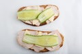 Isolated close up top view shot of a pair of two white bread turkey ham and cheese sandwiches with a slice of cucumber on top on a Royalty Free Stock Photo