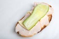 Isolated close up top view shot of a single white bread turkey ham and cheese sandwiches with a slice of cucumber on top on a Royalty Free Stock Photo