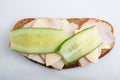 Isolated close up top view shot of a single white bread turkey ham and cheese sandwiches with a slice of cucumber on top on a Royalty Free Stock Photo