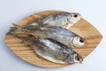 Isolated close up top view shot of three Russian dried salted vobla Caspian Roach fish on a wooden plate on a white background