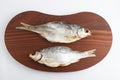 Isolated close up top view shot of two Russian dried salted vobla Caspian Roach fish on a dark wooden plate on a white Royalty Free Stock Photo