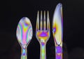 Isolated closeup shot of colorful holographic cutlery in front of a black background