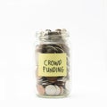 Isolated coins in jar with crowd funding label.