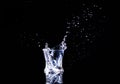 Isolated cold water in a glass with splash and cubes of ice on black background Royalty Free Stock Photo