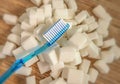 Isolated conceptual still life image of toothbrush over massive pile of sugar cubes in dental care and oral hygiene concept as war