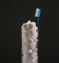 conceptual still life image of toothbrush and refreshment glass full of sugar cubes in dental care and oral hygiene conce